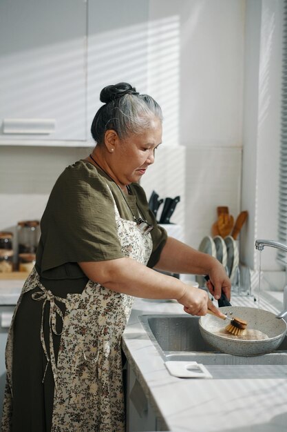 Housemaid washing dishes after cooking