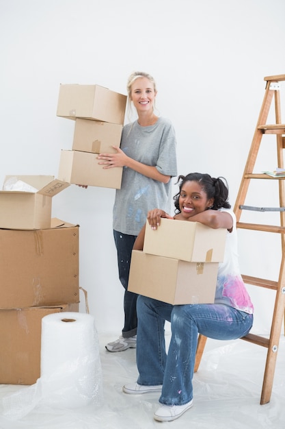 Photo housemates carrying cardboard moving boxes