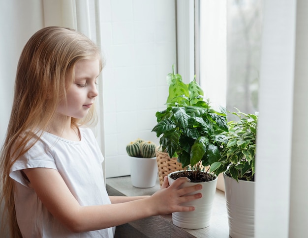 Cura delle piante d'appartamento, bambina che si prende cura delle piante d'appartamento