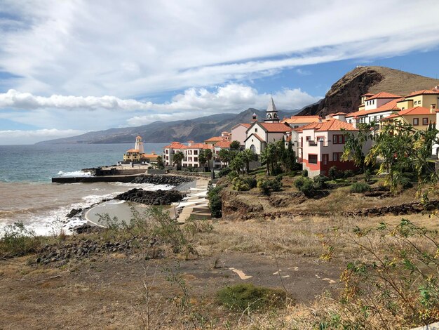 Houses on beach by buildings against sky