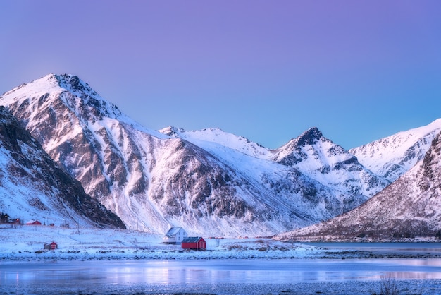 Houses and beautiful snow covered mountains in winter at dusk