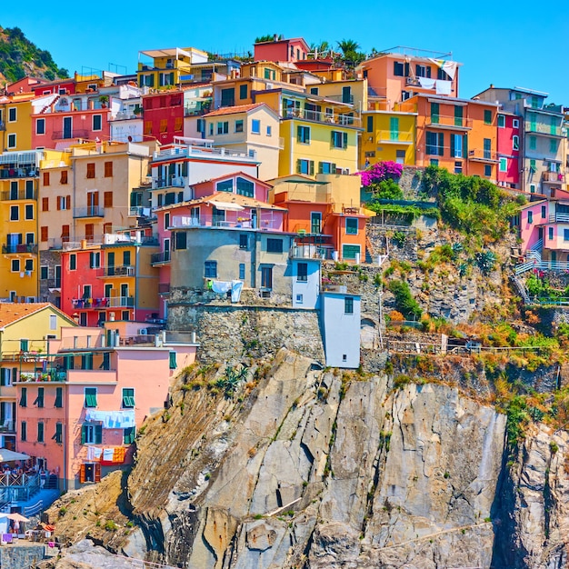 イタリア、ラ・スペツィア、チンクエテッレのマナローラの町の崖にある明るい色の家
