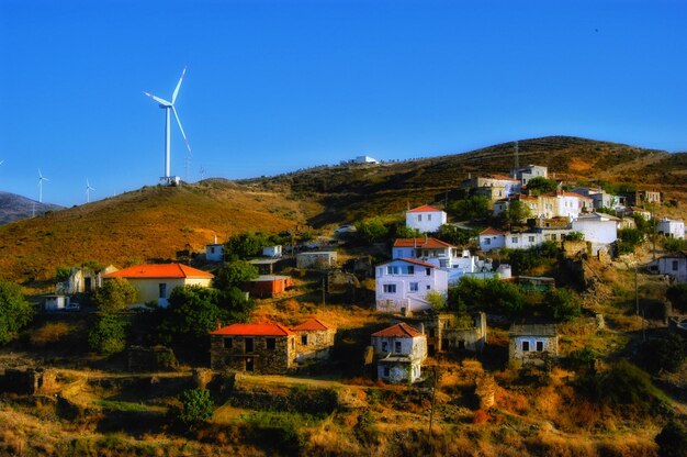 Houses by buildings against clear blue sky