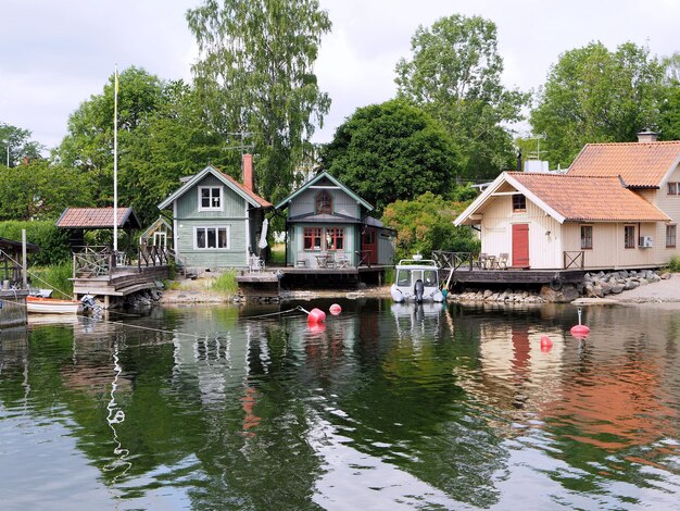 Houses by lake and buildings against sky