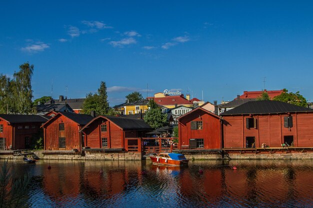 Houses by river and buildings against blue sky