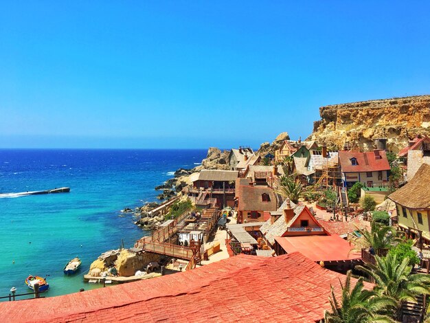 Houses by sea against clear blue sky