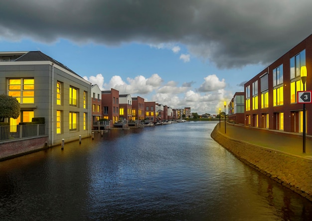 ランタンと窓からの光に照らされたオランダの都市 (オランダ、オランダ) の運河の家