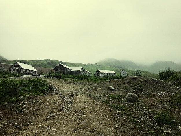 Houses on field against sky during foggy weather