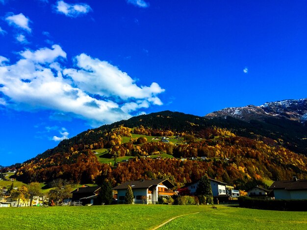 Houses on field by mountains against blue sky at schruns