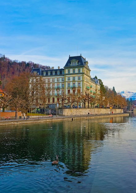 スイスのトゥーン旧市街の堤防にある家々と山々。トゥーンはスイスのベルン州にある都市です。トゥーン湖からアーレ川が流れ出る場所にあります。