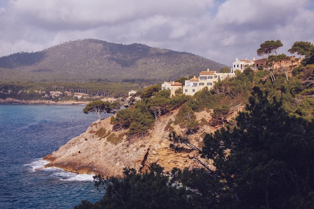 Foto case su formazioni rocciose in mare contro un cielo nuvoloso