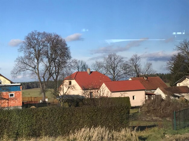 Houses and trees on field against sky