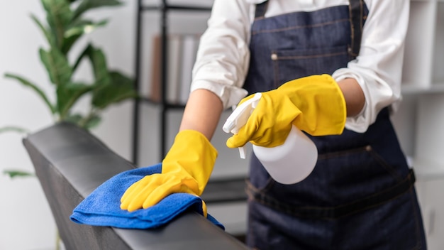 Photo housewife in apron wearing gloves to spraying hygiene spray on t