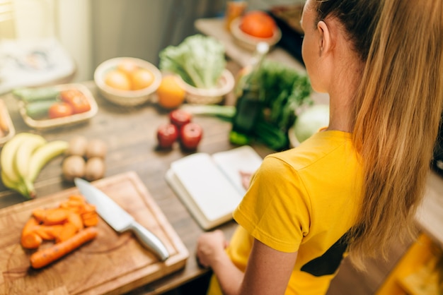 Хозяйка готовит на кухне здоровую экологически чистую пищу. Вегетарианская диета, свежие овощи и фрукты на деревянном столе