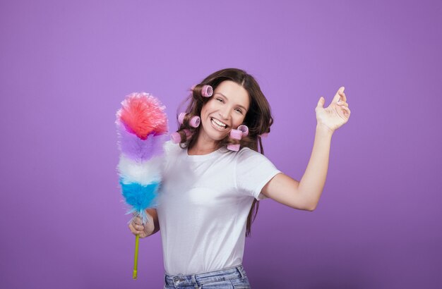 Housewife in curlers laughs and dances while cleaning.