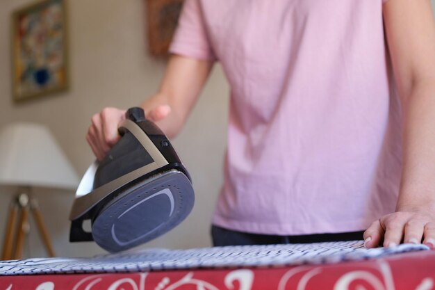 Housewife ironing bed linen on board using steam iron