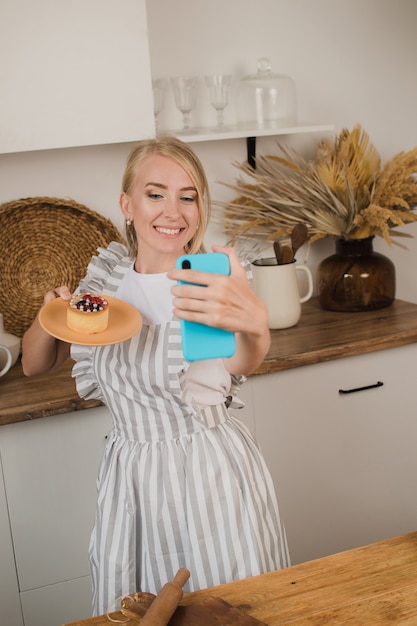 A housewife or pastry chef takes a selfie with dessert. Food blog. Cooking courses. Blogger woman