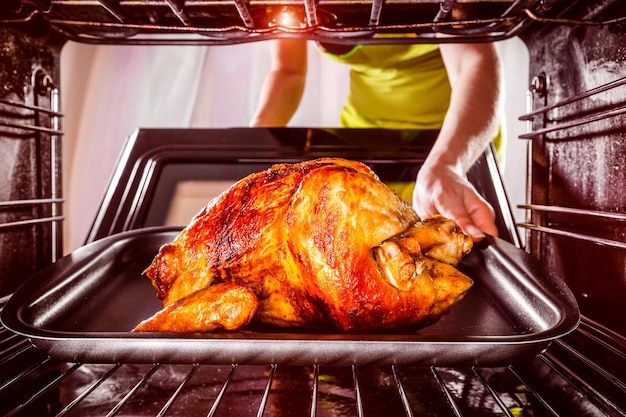 Photo housewife prepares roast chicken in the oven, view from the inside of the oven. cooking in the oven.