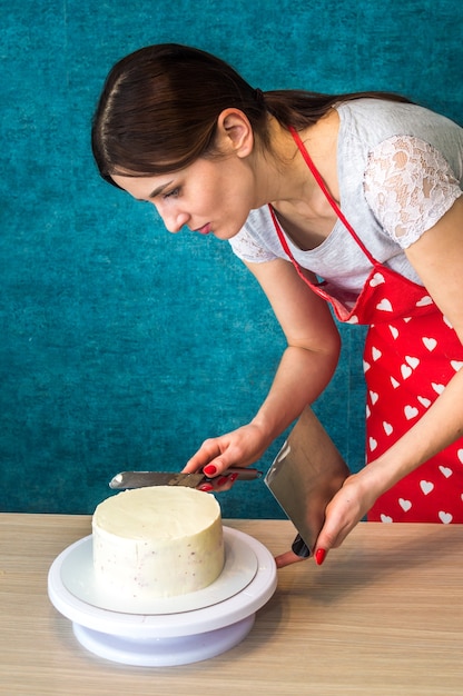 Photo housewife shapes sponge cake. close up. vertical photo