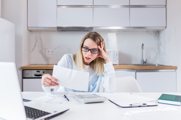 housewife sitting a table in house kitchen an incomprehensible deal with paperwork bills and loans