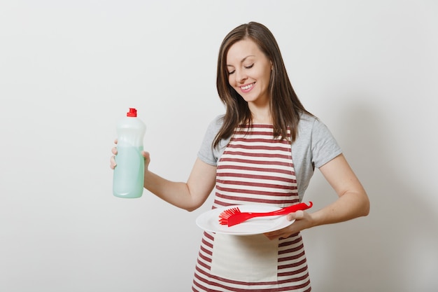 Housewife in striped apron isolated. Housekeeper woman holds bottle cleaner liquid, red brush for washing dishes, white empty round plate