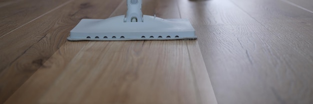 Housewife washing floor with steam brush at home closeup