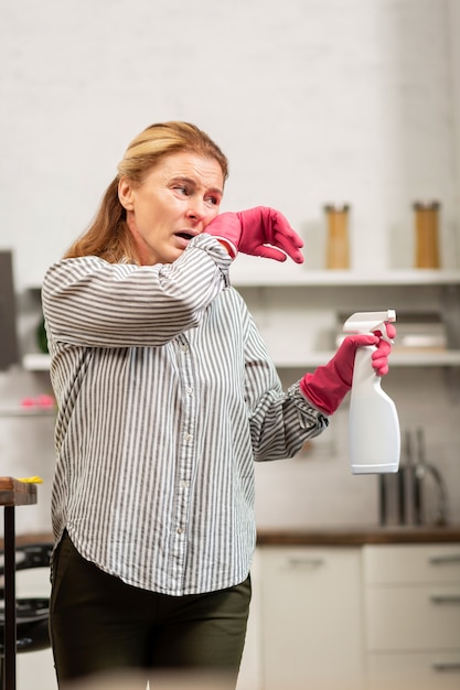 Housewife wearing dark trousers and striped shirt having allergy to dust