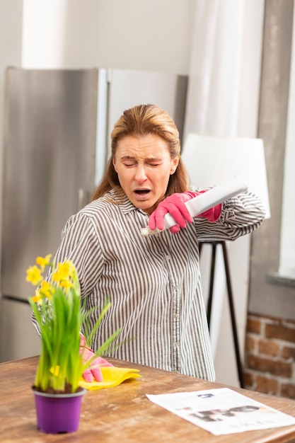 Housewife wearing striped shirt sneezing having allergy to flowers and chemicals