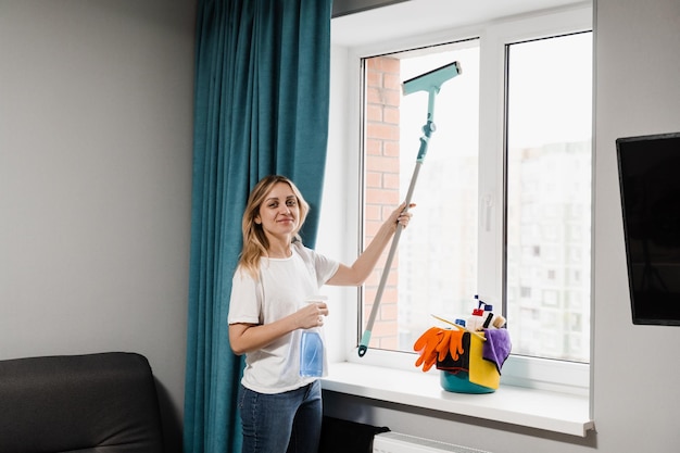 Housewife woman is cleaning at home and washing windows House cleaning service Housekeeper is spraying detergent and cleaning window at home