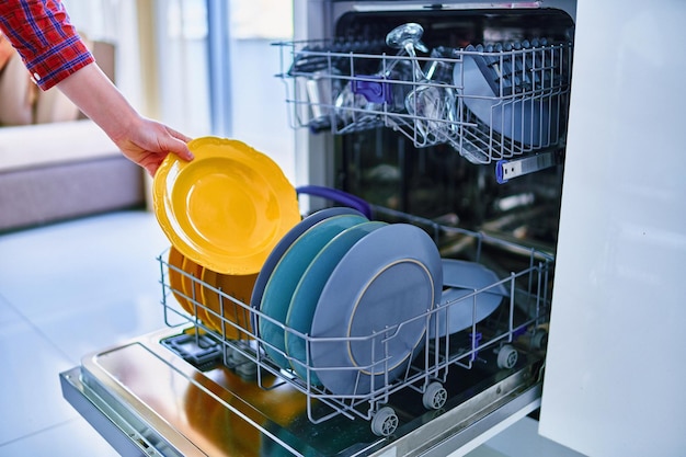 Housewife woman using modern dishwasher for wash dishes at home\
kitchen