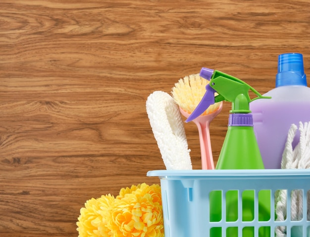 집안일 청소 및 잡일 나무 배경에 청소 제품 및 청소 도구가 있는 파란색 바구니 텍스트 복사 공간