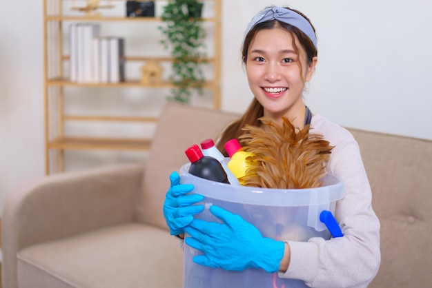 家事のコンセプト家政婦は手袋を着用し、掃除用品を持って家の掃除を準備します
