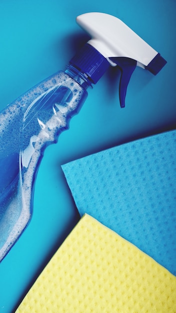 Работа по дому, ведение домашнего хозяйства и концепция домашнего хозяйства - тряпка для чистки, спрей для стирки на синем фоне