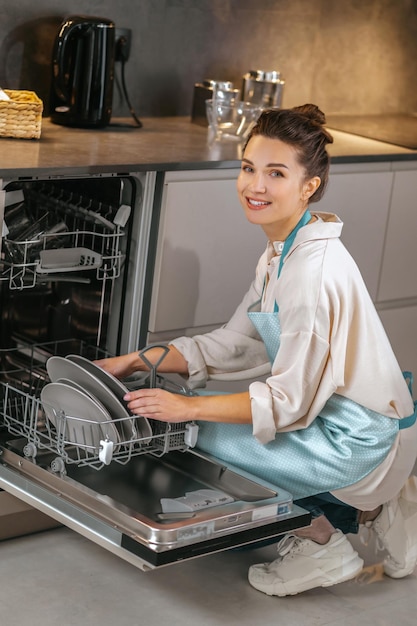 Housework. Housewife washing plates in the dishwasher