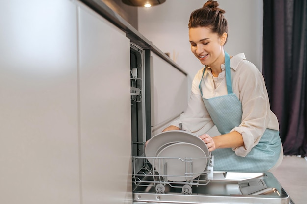 Housework. Housewife washing plates in the dishwasher