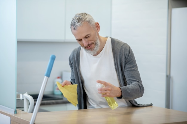 Lavori di casa. uomo in abiti da casa che fa i lavori domestici e sembra occupato