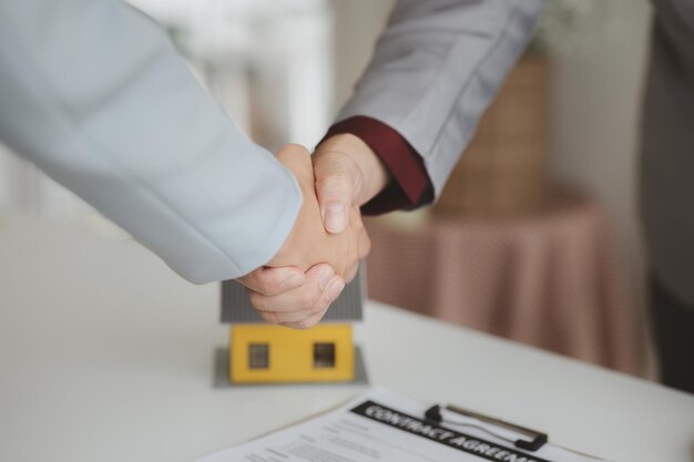 Housing estate agents shake hands with customers after a deal is completed explaining and presenting information about homes and purchasing loans Real estate trading concept