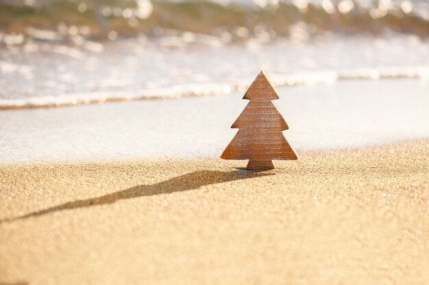 Hout houten kerstboom op een zand op het tropische strand in de buurt van de oceaan