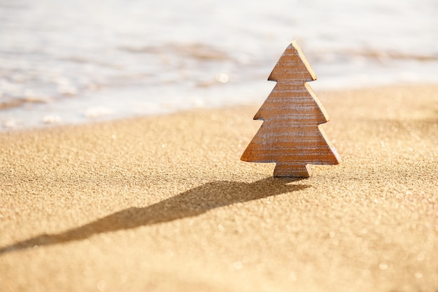 Hout houten kerstboom op een zand op het tropische strand in de buurt van de oceaan