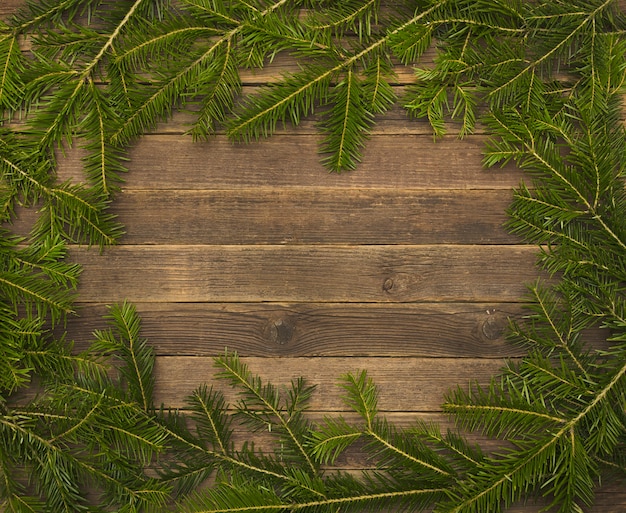 Houten achtergrond met dennentakken op de rand.