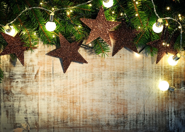 Foto houten achtergrond met fir twijgen, sterren en kerstverlichting