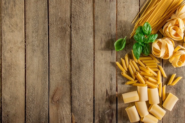 Foto houten achtergrond met italiaanse pasta en basilicum