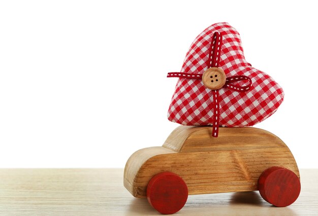 Houten auto met een rood stoffen hart op een witte houten tafel