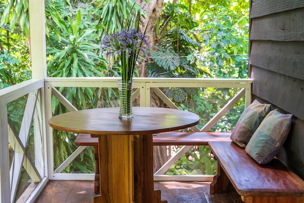 Houten bank met kussens en tafel met een vaas met bloemen op een houten veranda Tanzania Afrika close-up