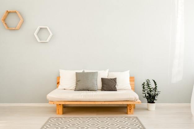 Houten bank met kussens in woonkamer in Scandinavische stijl met ronde salontafel en ficusplant