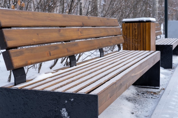 Houten banken in het park onder de sneeuw. Winterseizoen, koud weer.