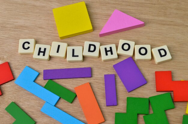 Houten blokken en vierkante letters met tekst CHILDHOOD over houten achtergrond