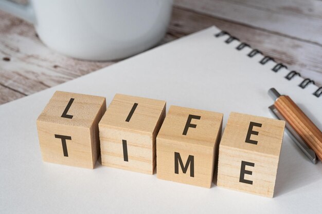 Foto houten blokken met life en time tekst van concept, een pen, een notitieboekje en een kopje.