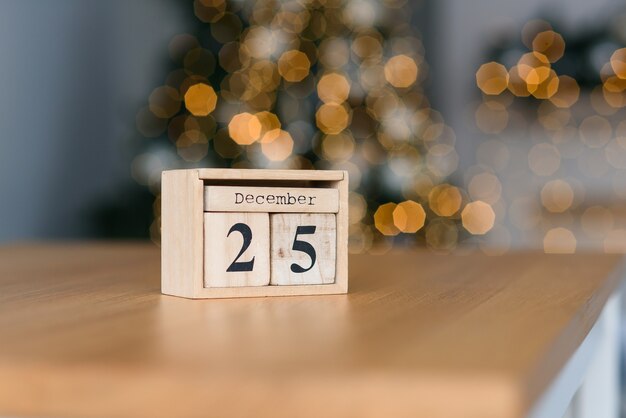 Foto houten blokkenkalender met de datum van 25 december op de kerstverlichting. wintervakantie stemming.