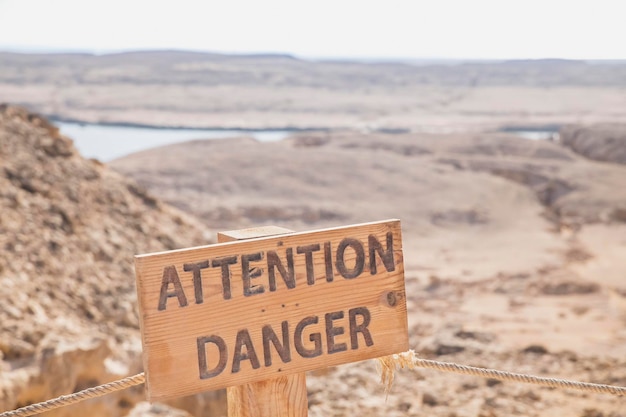 houten bord Let op bovenop een klif in de woestijn in Egypte
